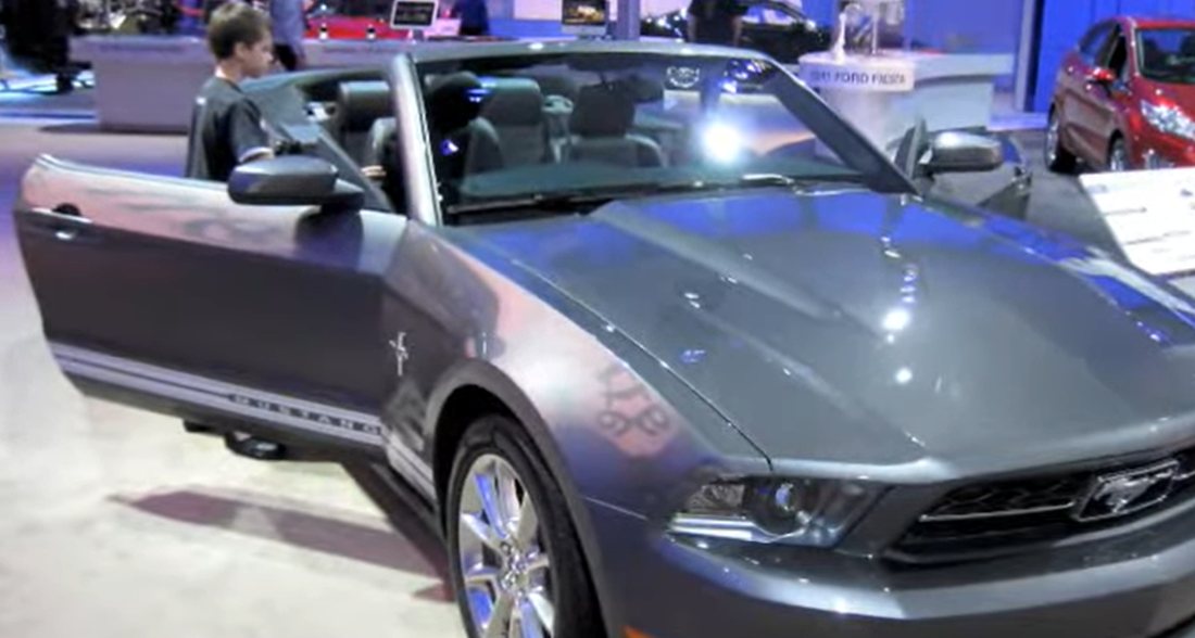 A ten-year-old JP climbing into a grey Mustang convertible at the 2010 Detroit auto show